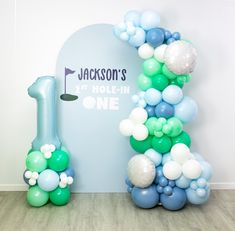 balloons are arranged in the shape of a golf hole and number one balloon arch for a birthday party