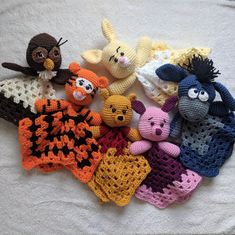 several crocheted stuffed animals laying on top of a white blanket next to each other