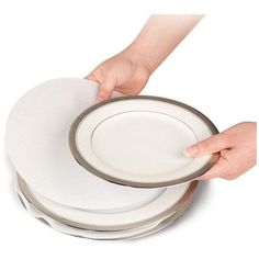 a stack of white plates being held by someone's hand with their thumb on the plate