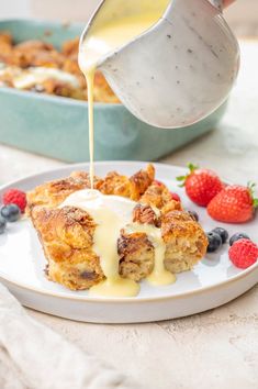 someone is pouring syrup on some food with berries and strawberries in the foreground