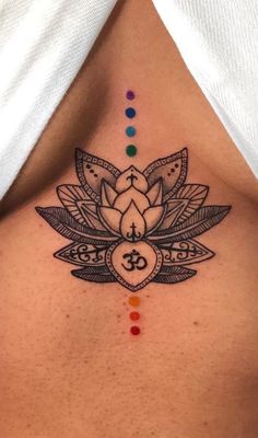 a woman's chest with a lotus tattoo on the top and seven chakras