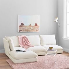 a living room with a white couch and pink rug