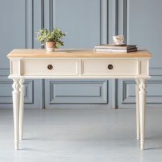 a white table with two drawers and a potted plant on top