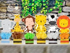 paper cutouts of animals and giraffes in front of a stone wall