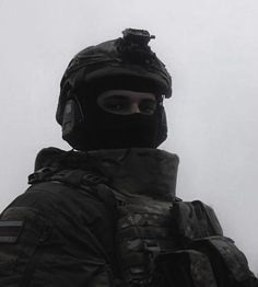 a man wearing a helmet and goggles standing in front of a building on a foggy day