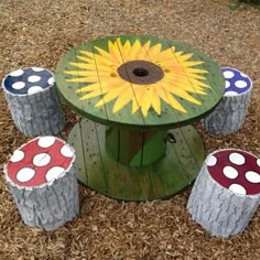 an outdoor table made out of logs and painted with sunflowers