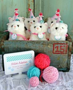 four stuffed animals are in a box with yarn and balls of yarn next to it