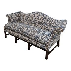 a blue and white patterned couch sitting on top of a wooden frame with an arm rest