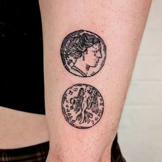 a woman's arm with two coin tattoos on it