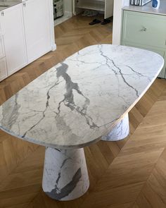 a white marble table in a kitchen with herring wood flooring and an island countertop