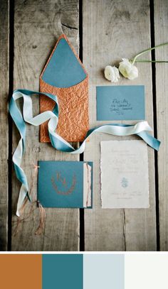 the wedding stationery is blue and orange, with white flowers on each one side