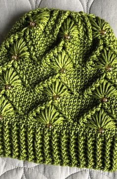 a green knitted hat sitting on top of a bed