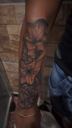 a woman's leg with tattoos on it and flowers in the middle of her arm