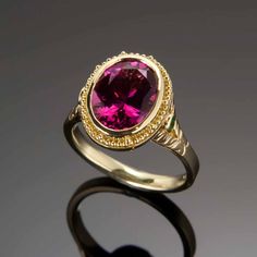 Exquisitely handcrafted in granulated 18KY gold, the “flower” of this one-of-a-kind ring is a 3.13ct rubellite tourmaline. Butterflies created in 18KW and each set with a 1.3mm VS/GH diamond are found on either side of the center gemstone. 2mm tsavorite garnets and the engraved leaf pattern create the flower’s stalk on the shank as engraved butterflies on the shank and beneath the center stone all flutter to the dazzling raspberry-red of the luscious rubellite tourmaline. Size 5.5, but each ring Yellow Gold Ruby Ring With Tourmaline Center Stone, Rubellite Tourmaline, Raspberry Red, Tsavorite Garnet, Butterfly Ring, The Butterfly, Leaf Pattern, Tourmaline, Garnet