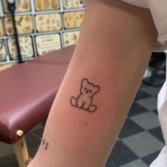 a small teddy bear tattoo on the arm