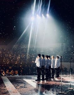 a group of men standing on top of a stage in front of an audience at a concert