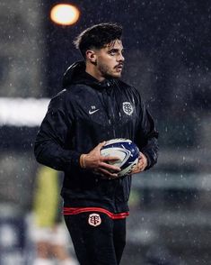 a man holding a soccer ball in the rain