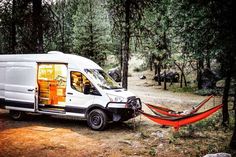 a white van parked in the woods next to a hammock