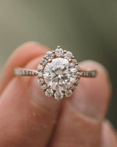 a woman's hand holding an engagement ring with a diamond center in the middle