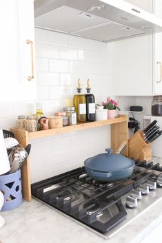 a stove top oven sitting inside of a kitchen next to a counter with cooking utensils on it