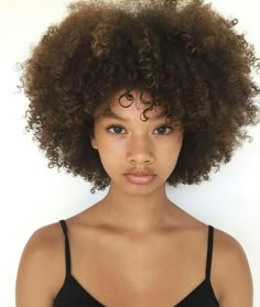 a close up of a person wearing a bra with an afro hairdo and blue eyes