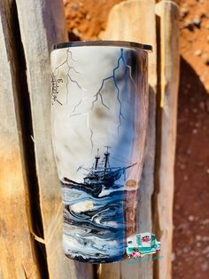 a cup that is sitting on top of a wooden post with a boat in the water