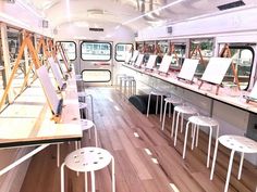 the inside of a bus with tables and stools on it's sides, as well as mirrors