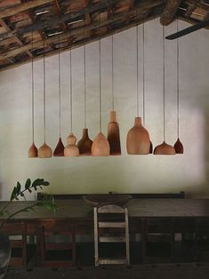 a number of vases hanging from a ceiling in a room with wooden tables and chairs