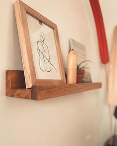 a wooden shelf with a drawing on it next to a lamp and other items in the background