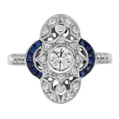 Wonderful and very special antique design ring, modeled in 18K White gold. It is decorated with an approx. central 0.35 carat round diamond. The main stone is surrounded by diamonds and half circle lines of French cut blue sapphire on both side. Two elements make this ring special and unique. Ring Information Style: Art Deco Metal: 18K White Gold Weight: 4.70 g. (approx. total weight) Center Gemstones Type: Diamond Shape: Round Average Color: H Average Clarity: SI Size: 4.5 mm. Number: 1 Weight: Sapphire Ring Vintage 1stdibs, Blue Multi-stone Sapphire Ring In Art Deco Style, Blue Diamond Ring, Art Deco Style, Gift, Luxury Vintage Sapphire Cabochon Ring, Exquisite 14k White Gold Sapphire Ring, Round Cut, French Cut, Estilo Art Deco, Antique Design, Cluster Ring