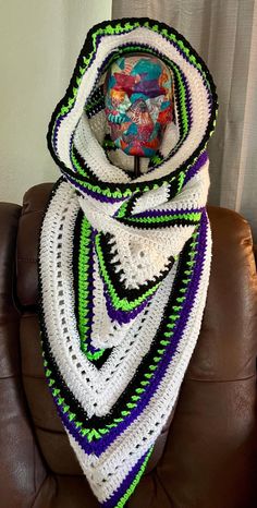 a crocheted scarf is sitting on a brown chair