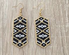 black and white beaded earrings with gold accents on a wooden surface, the beads are hanging from hooks