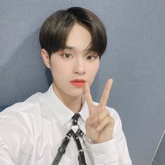 a young man wearing a white shirt and tie making the v sign with his fingers