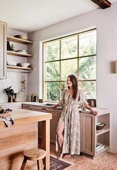 a woman standing in a kitchen next to a window