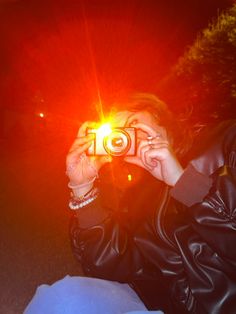 a woman holding up a camera to take a photo with the sun shining behind her