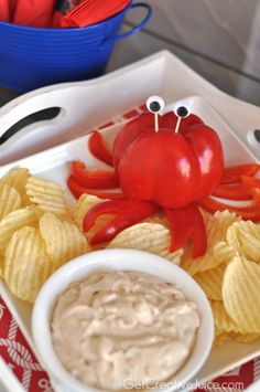 a crab and potato chips with dipping sauce in the middle on a tray next to a bowl of dip