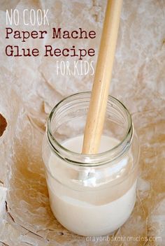 a glass jar filled with white liquid next to a wooden spoon and paper mache