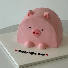 a pink pig cake sitting on top of a white plate