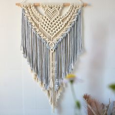 a macrame hanging on a wall next to flowers