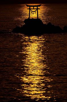 the sun is setting over the water with a small island in the foreground and a floating shrine on it