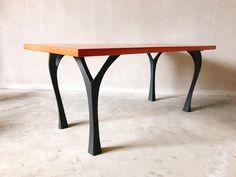 a wooden table sitting on top of a white floor next to a brown and black wall