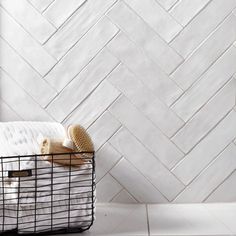 a basket that has some towels in it on the floor next to a white tiled wall