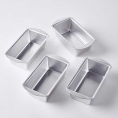 four metal pans sitting next to each other on a white surface with no one in them