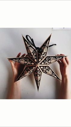 someone is holding up a paper star ornament to show it's intricate design