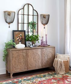 a room with a rug, mirror and vases on the floor in front of it