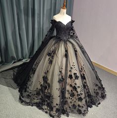 Timeless vintage-inspired Black Sweetheart Quinceanera Dress. Featuring an intricate beadwork bodice, off-the-shoulder long sleeves with a dramatic floral drape shoulder cape, this dress exudes glamour and luxury. The black lace overlay complete with hand sewn florals adds a touch of elegance, while the adjustable lace-up back ensures a perfect fit. Elevate your party look with this exquisite ball gown. material: glitter tulle, organza type: ball gown style: formals color as shown built in bra s