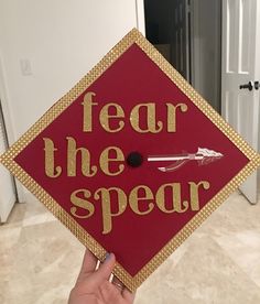 a red and gold graduation cap that says fear the spear