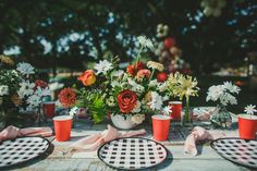 a table topped with plates and vases filled with flowers