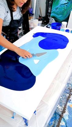 a woman is cutting out blue and white artwork