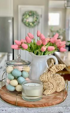 pink tulips in a white vase and some eggs on a tray